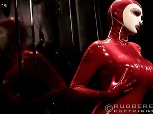 Игривая сучка в красном латексе сексуально позирует перед зеркалом