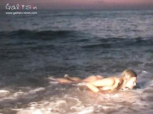 Молодая красотка плещется голышом в море на закате солнца