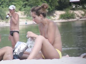 Девушка сняла лифчик на пляже и беседует по телефону