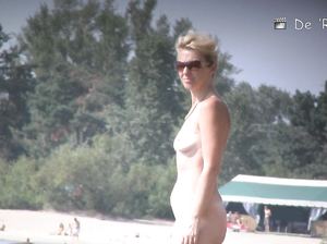 Нудисты прогуливаются голышом около пляжных домиков