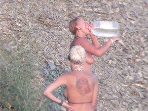 Обнаженные девушки моются под душем на общественном пляже