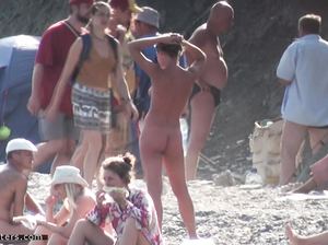 Вуайерист подглядывает за голой женщиной на нудистском пляже