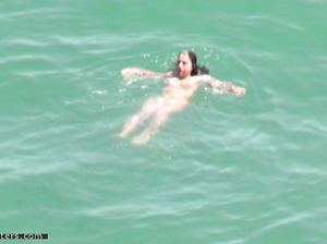 Обнаженная брюнетка без стеснения плескается в море