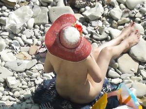 Дама в панамке и без одежды загорает на пляже