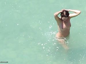 Парень подгялывает за голыми парами, которые купаются в море