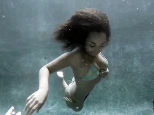 Темнокожая красотка тренируется подольше находиться под водой