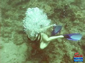 Обнаженная аквалангистка ищет сокровища на дне океана