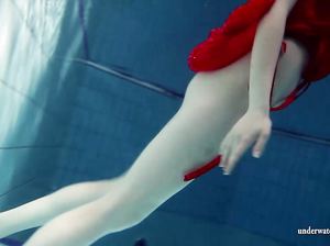 Блондинка в красном платье на голое тело ныряет в бассейне