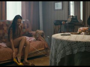 Обнаженная малышка увлеченно говорит по телефону