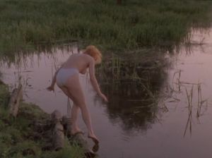Игривая девка купается в озере с голыми сиськами