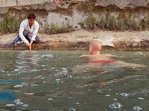 Бритая наголо деваха плавает в реке с голыми сиськами