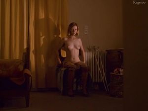 Задумчивая девушка раздевается и разглядывает себя в зеркало